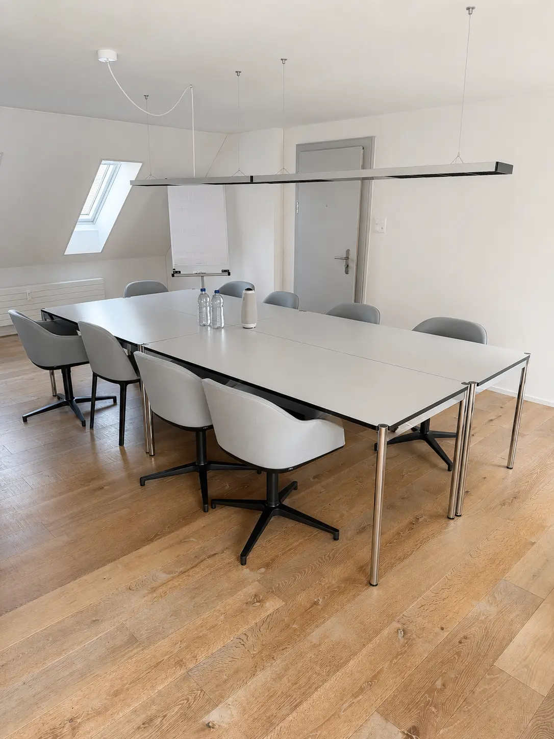 Sitzungsraum mit langem Tisch, Flipchart, Dachfenster und Tageslicht